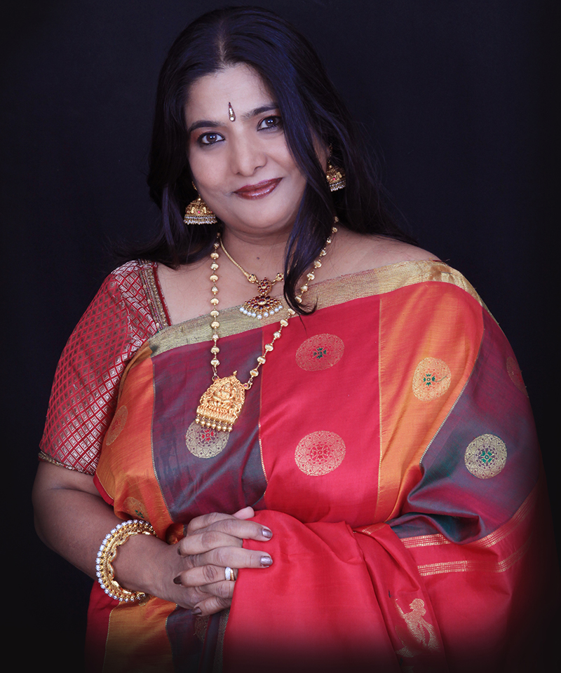 Dr Veena Murthy Vijay — full-length portrait in performance attire, three-quarter profile, stage wash